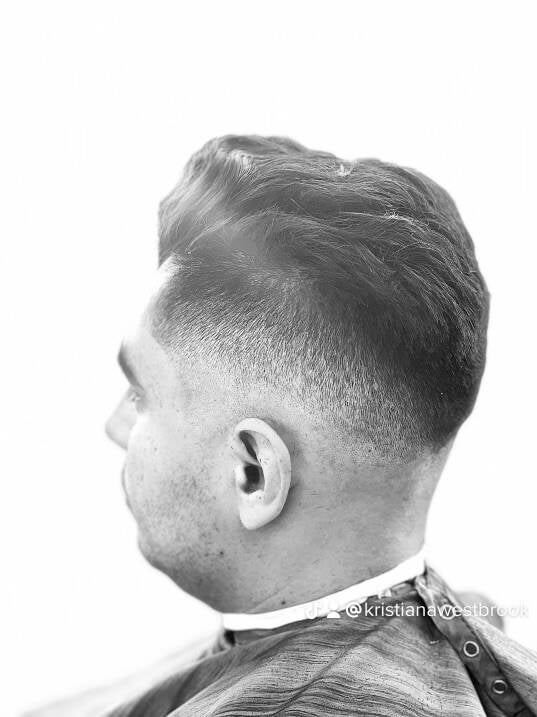 Black and white profile of a slicked-back cut with a clean skin fade.