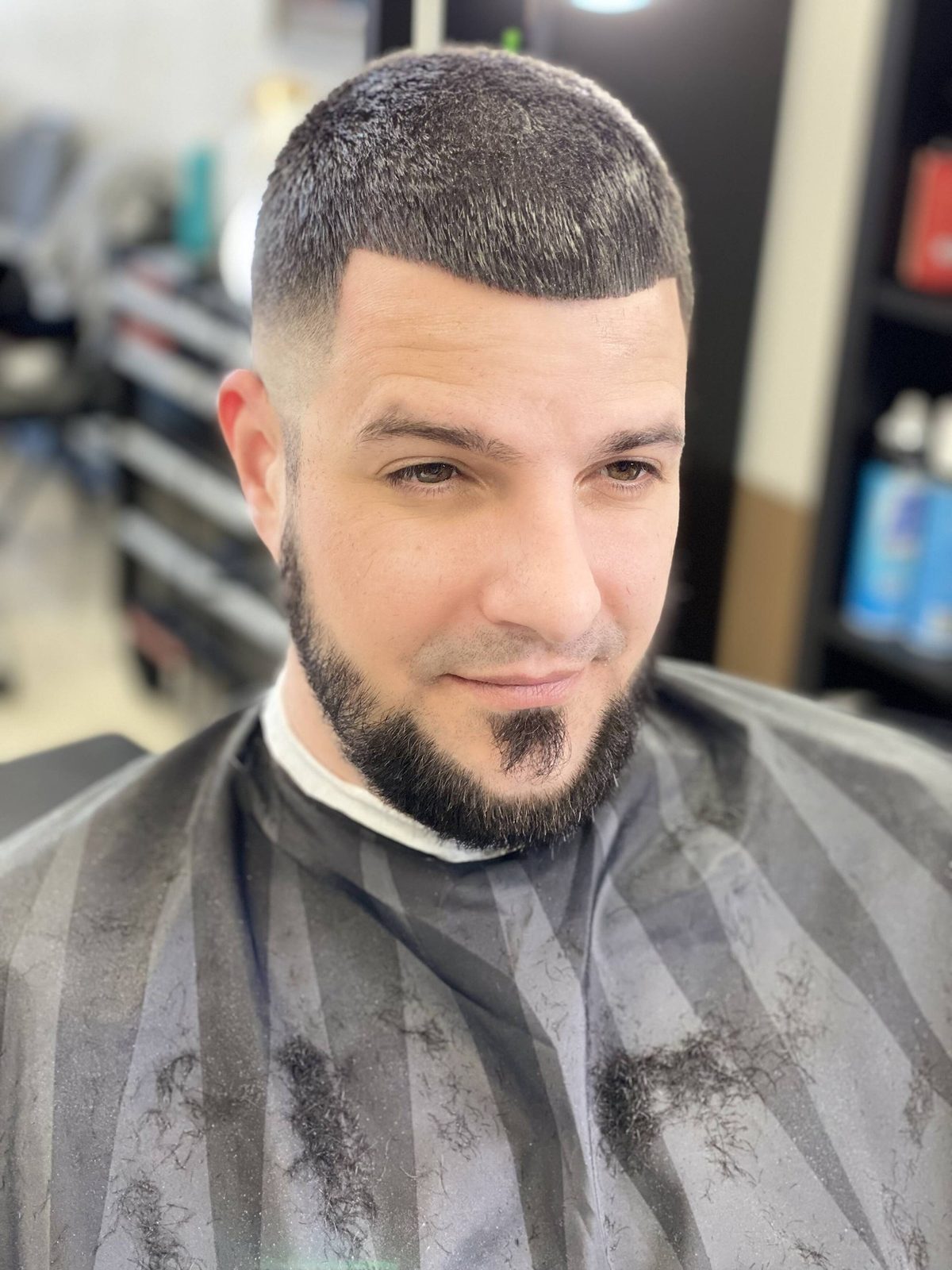 A client with a sharp mid fade and a shaped, lined-up beard after his cut at Love More Cutz.