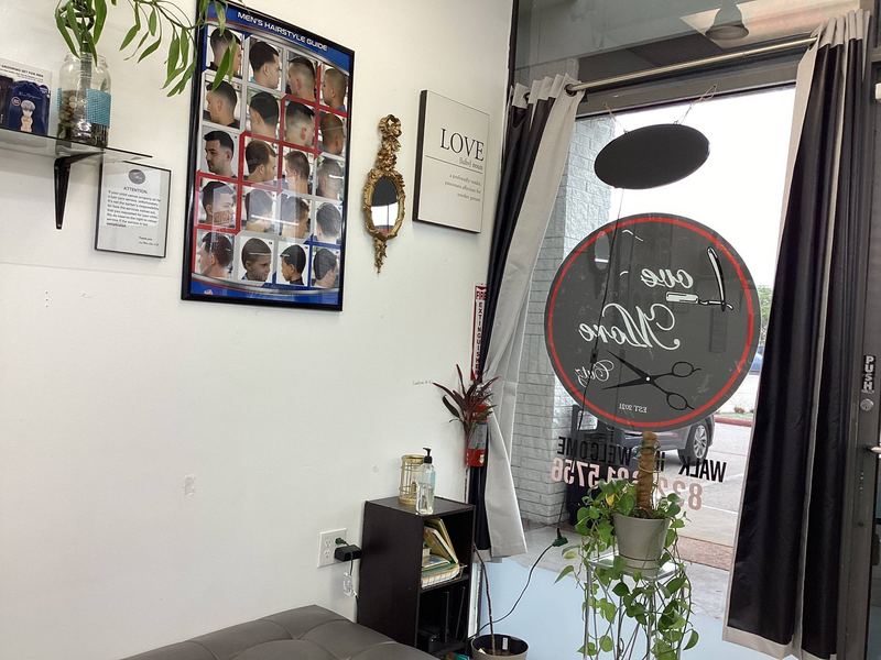 A corner of the shop with the Love More Cutz wall decal and framed certificates.